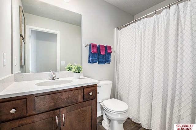 bathroom with a textured ceiling, wood-type flooring, vanity, and toilet