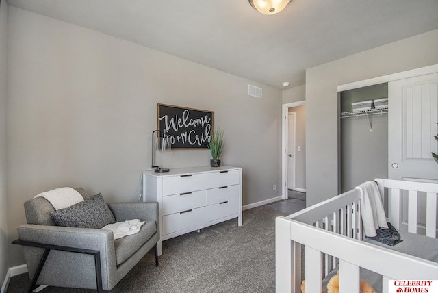 bedroom featuring a crib, a closet, and dark colored carpet