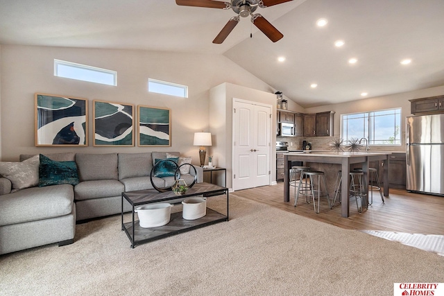 living room featuring sink, high vaulted ceiling, ceiling fan, and light wood-type flooring