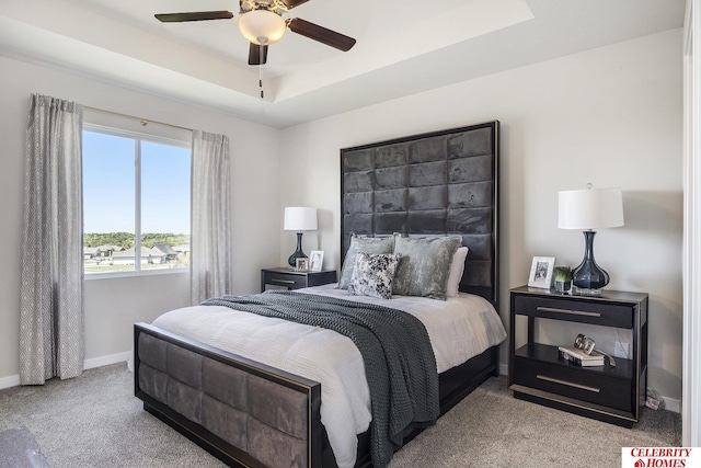 carpeted bedroom featuring ceiling fan and a tray ceiling