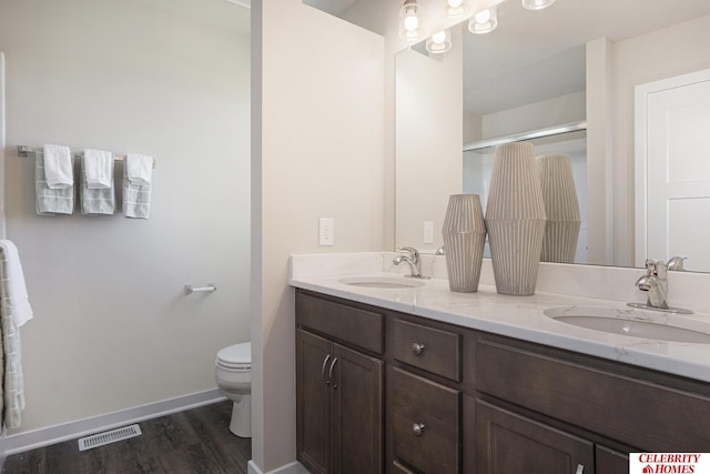 bathroom featuring toilet, wood-type flooring, vanity, and walk in shower