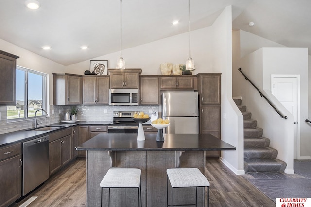 kitchen featuring pendant lighting, a kitchen island, backsplash, a breakfast bar area, and appliances with stainless steel finishes