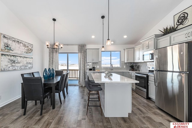 kitchen with stainless steel appliances, vaulted ceiling, pendant lighting, and a center island