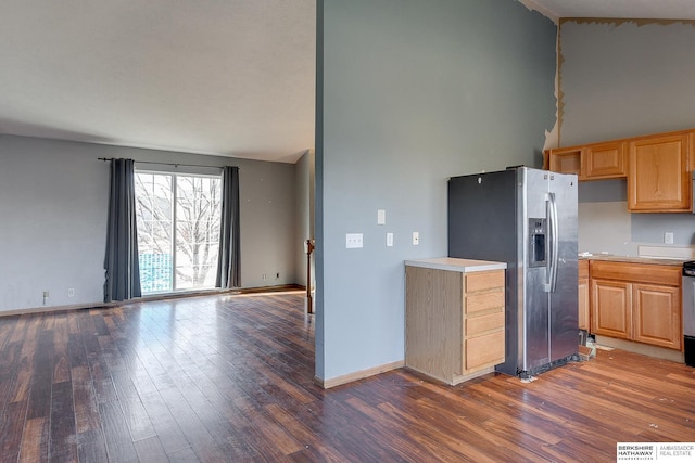 kitchen with dark wood-type flooring, stove, vaulted ceiling, and stainless steel fridge