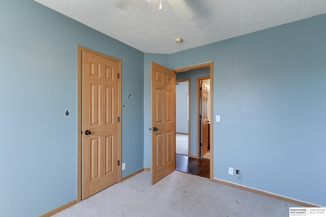 unfurnished bedroom featuring ceiling fan, a textured ceiling, and light carpet