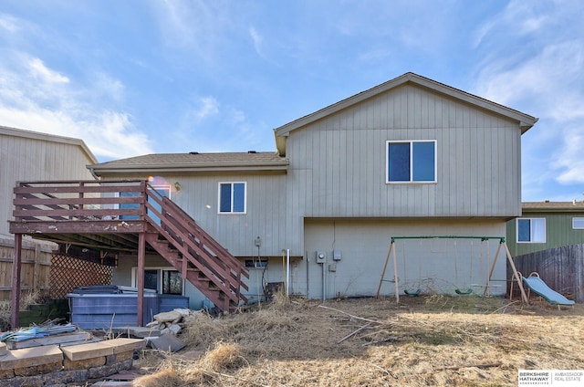 rear view of property featuring a deck and a hot tub