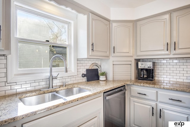 kitchen with light stone counters, dishwasher, backsplash, and sink