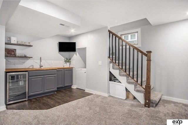 bar featuring beverage cooler, dark colored carpet, gray cabinetry, sink, and butcher block counters