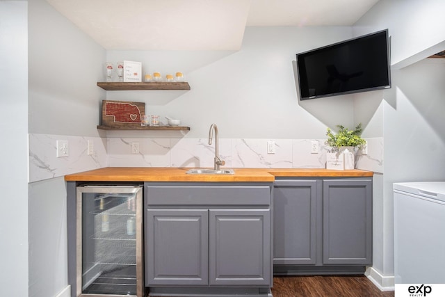 bar featuring butcher block counters, beverage cooler, and gray cabinetry