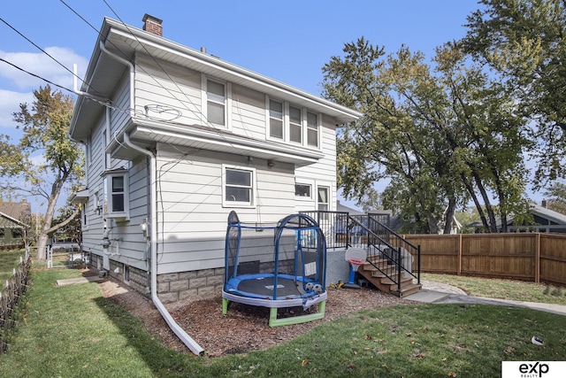 back of property with a lawn and a trampoline