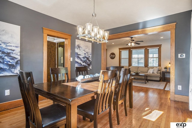 dining room featuring ceiling fan with notable chandelier and light hardwood / wood-style floors