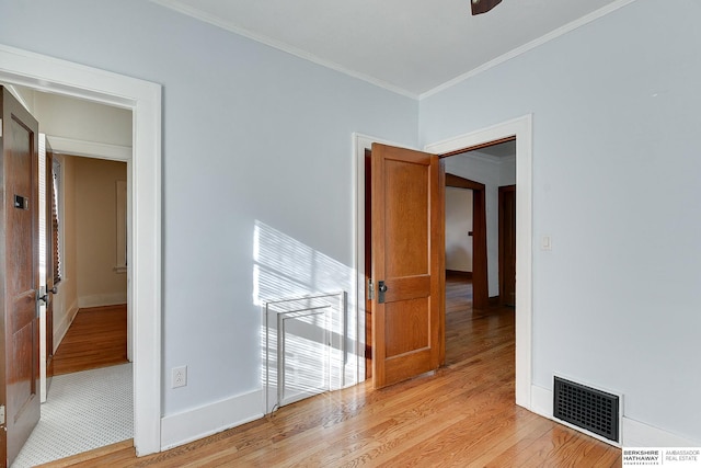 empty room with light wood-type flooring and crown molding