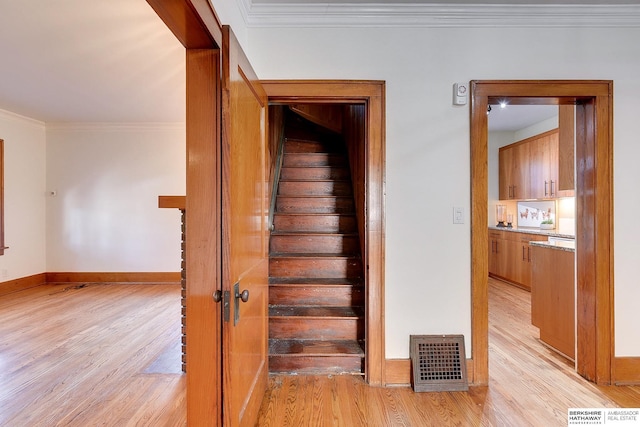 staircase with hardwood / wood-style floors and crown molding