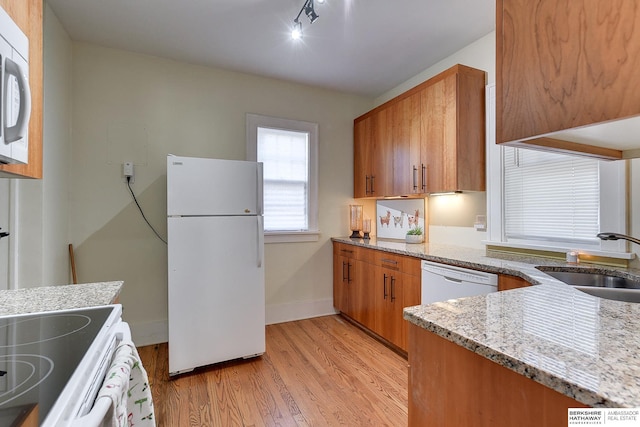 kitchen with sink, white appliances, light hardwood / wood-style floors, and light stone countertops