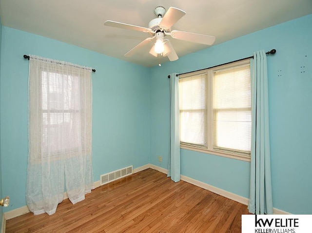 spare room with ceiling fan, light wood-type flooring, and a wealth of natural light