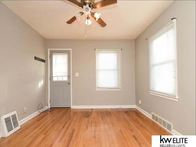 interior space with light wood-type flooring, ceiling fan, a textured ceiling, and a healthy amount of sunlight