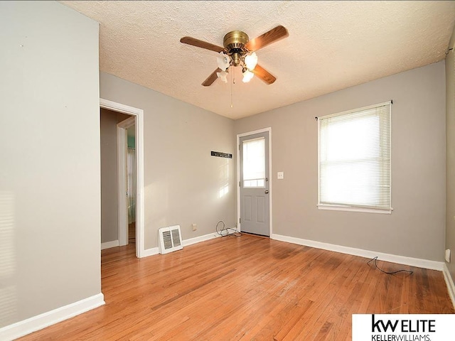 empty room featuring a textured ceiling, ceiling fan, and light hardwood / wood-style floors