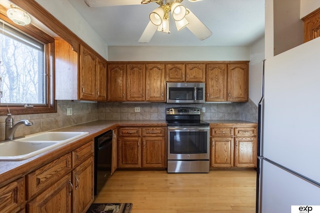 kitchen featuring decorative backsplash, sink, appliances with stainless steel finishes, and light wood-type flooring