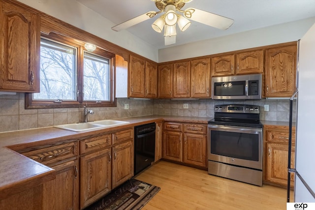 kitchen with appliances with stainless steel finishes, decorative backsplash, light hardwood / wood-style flooring, and sink