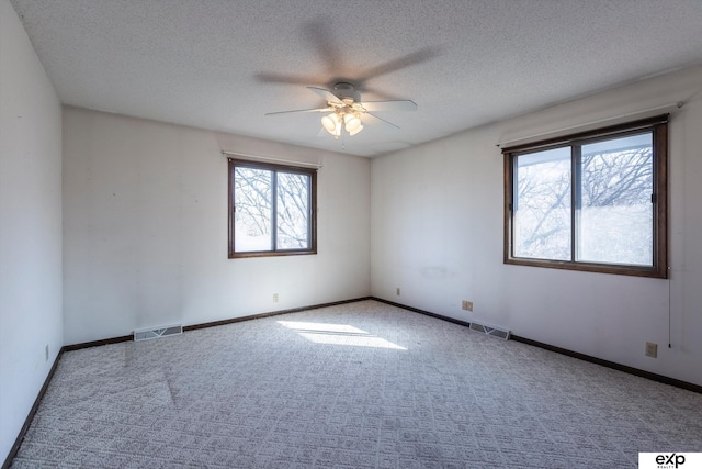 carpeted spare room featuring ceiling fan and a textured ceiling