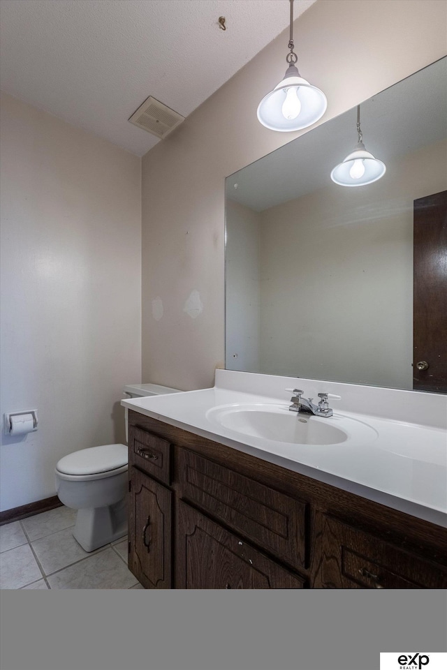 bathroom with toilet, vanity, and tile patterned flooring