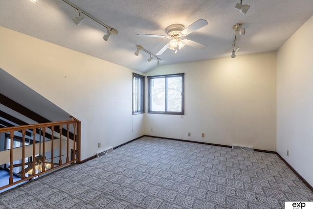 unfurnished room with ceiling fan, track lighting, a textured ceiling, vaulted ceiling, and carpet flooring