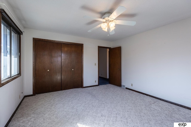 unfurnished bedroom featuring ceiling fan, a closet, and light carpet