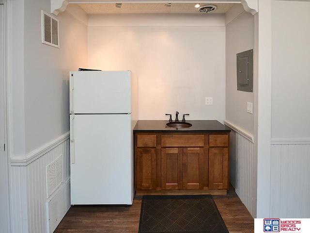 kitchen featuring white fridge, dark wood-type flooring, electric panel, and sink