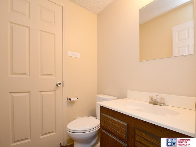 bathroom with toilet, vanity, and a textured ceiling