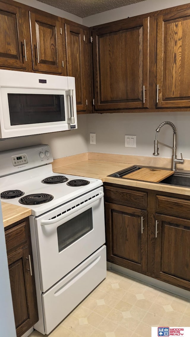 kitchen featuring sink, white appliances, and dark brown cabinetry