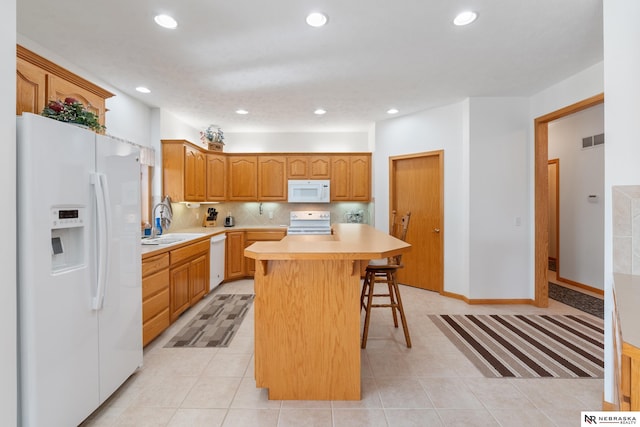 kitchen featuring decorative backsplash, a center island, white appliances, a breakfast bar, and sink