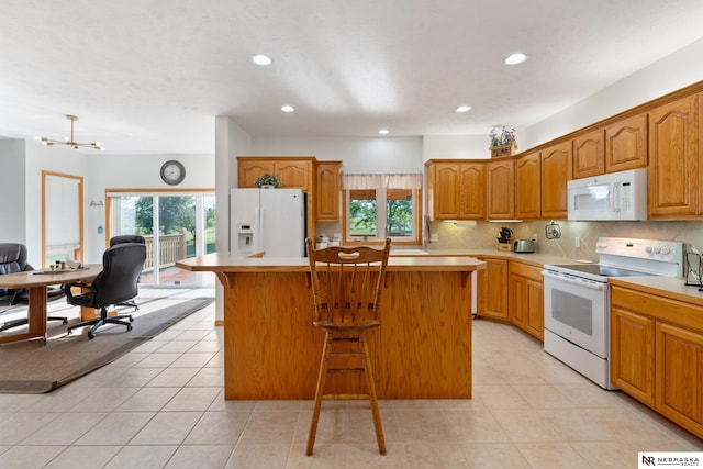 kitchen with backsplash, a notable chandelier, a kitchen island, a kitchen bar, and white appliances