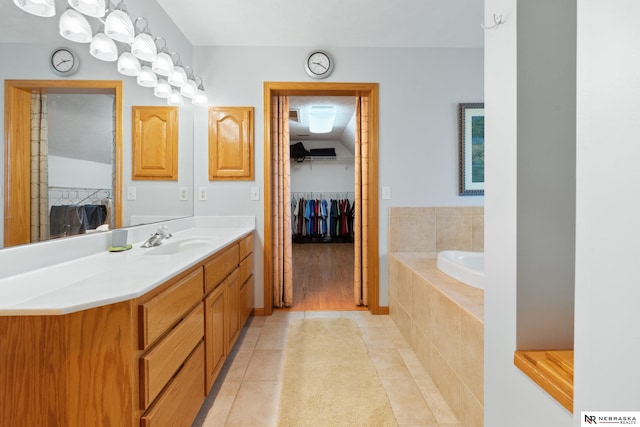 bathroom featuring tile patterned floors, vanity, and a relaxing tiled tub