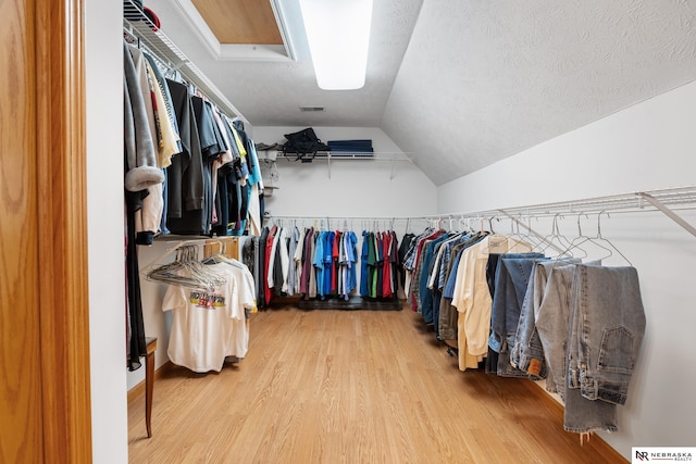 walk in closet with hardwood / wood-style flooring and vaulted ceiling