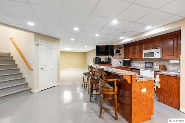 kitchen with white appliances, a kitchen island, tasteful backsplash, a kitchen breakfast bar, and sink