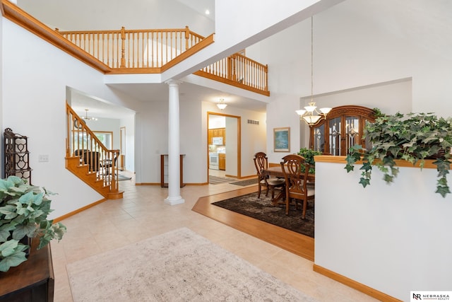 tiled dining room with an inviting chandelier, a high ceiling, and decorative columns