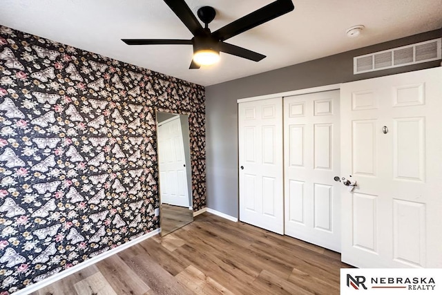 unfurnished bedroom with ceiling fan, hardwood / wood-style floors, and a closet