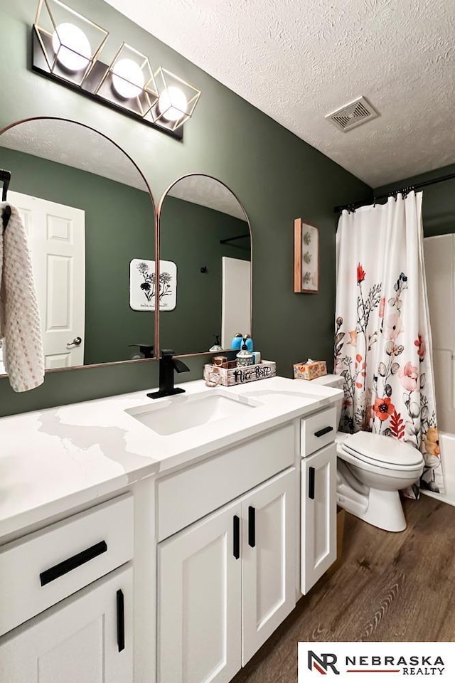 full bathroom featuring toilet, vanity, wood-type flooring, a textured ceiling, and shower / tub combo with curtain