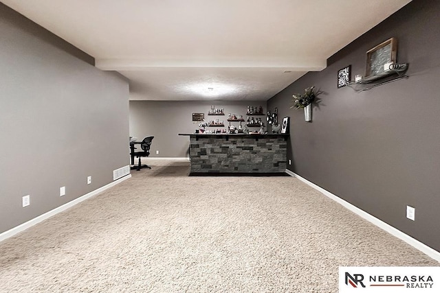 unfurnished room with beamed ceiling, bar, and carpet flooring