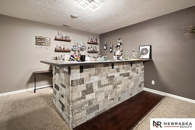 bar featuring a textured ceiling and carpet flooring