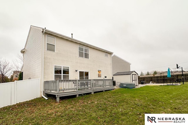 rear view of property with a yard, a deck, and a storage unit