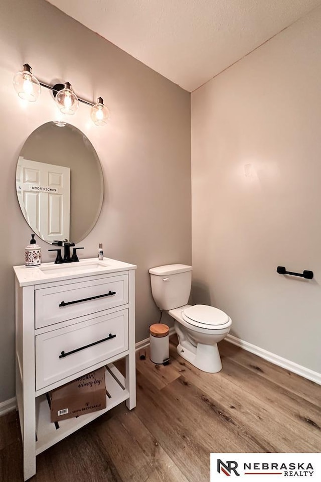 bathroom with toilet, vanity, and wood-type flooring