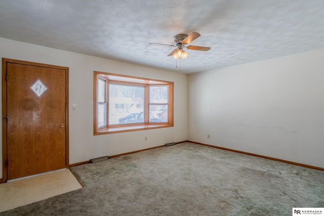 foyer with carpet floors, a ceiling fan, visible vents, and baseboards