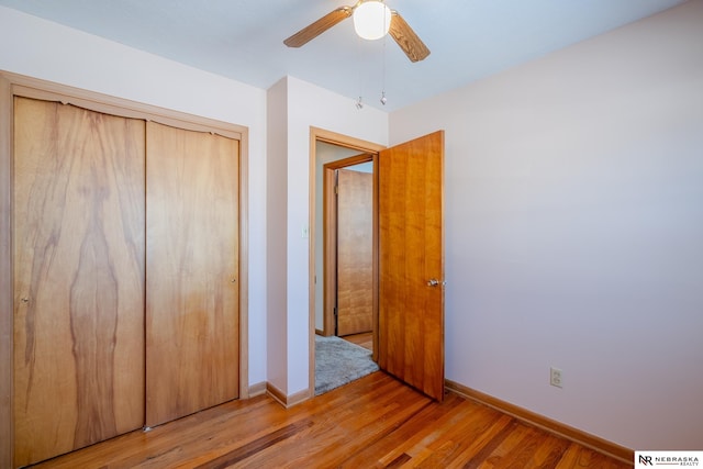 unfurnished bedroom featuring a ceiling fan, baseboards, a closet, and wood finished floors