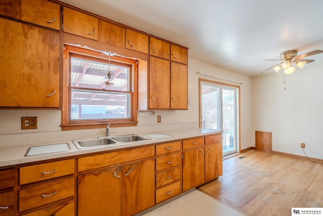 kitchen featuring brown cabinets, light countertops, a sink, and light wood finished floors