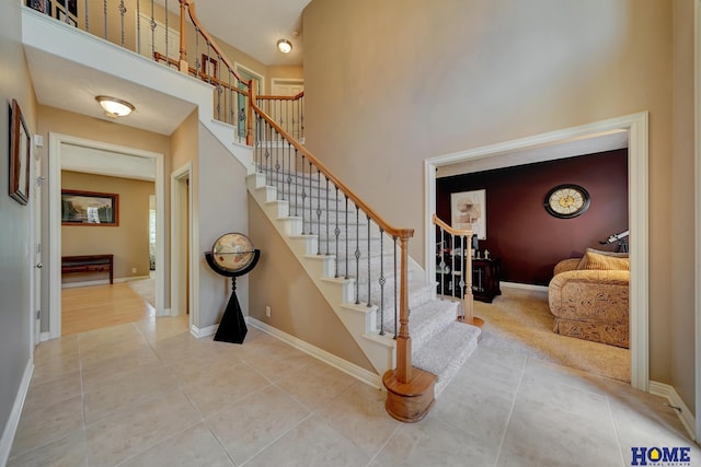 stairs with tile patterned floors and a towering ceiling