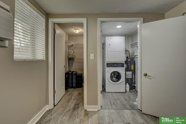 clothes washing area with a textured ceiling, light hardwood / wood-style flooring, and stacked washer and dryer