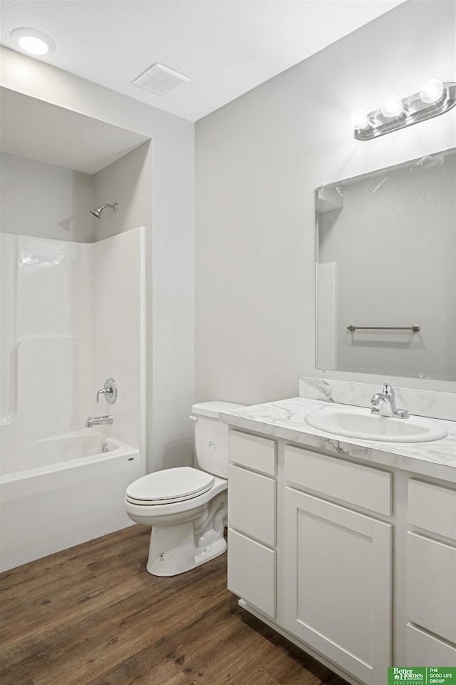 full bathroom featuring hardwood / wood-style floors, shower / tub combination, vanity, and toilet