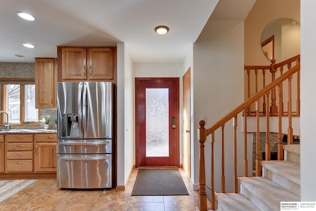 kitchen with light stone counters and stainless steel fridge