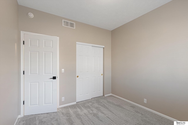 unfurnished bedroom featuring light carpet and a closet